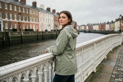 Femme sur le Ha'penny Bridge à Dublin regardant la rivière Liffey par temps nuageux typique irlandais