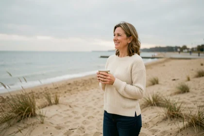 Femme en pull tricoté profitant d'une plage déserte en basse saison lors d'une escapade Iris Vacance