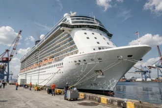 Vue grand angle du plus grand bateau de croisière au monde amarré dans un port, avec des dockers au premier plan pour illustrer son échelle impressionnante